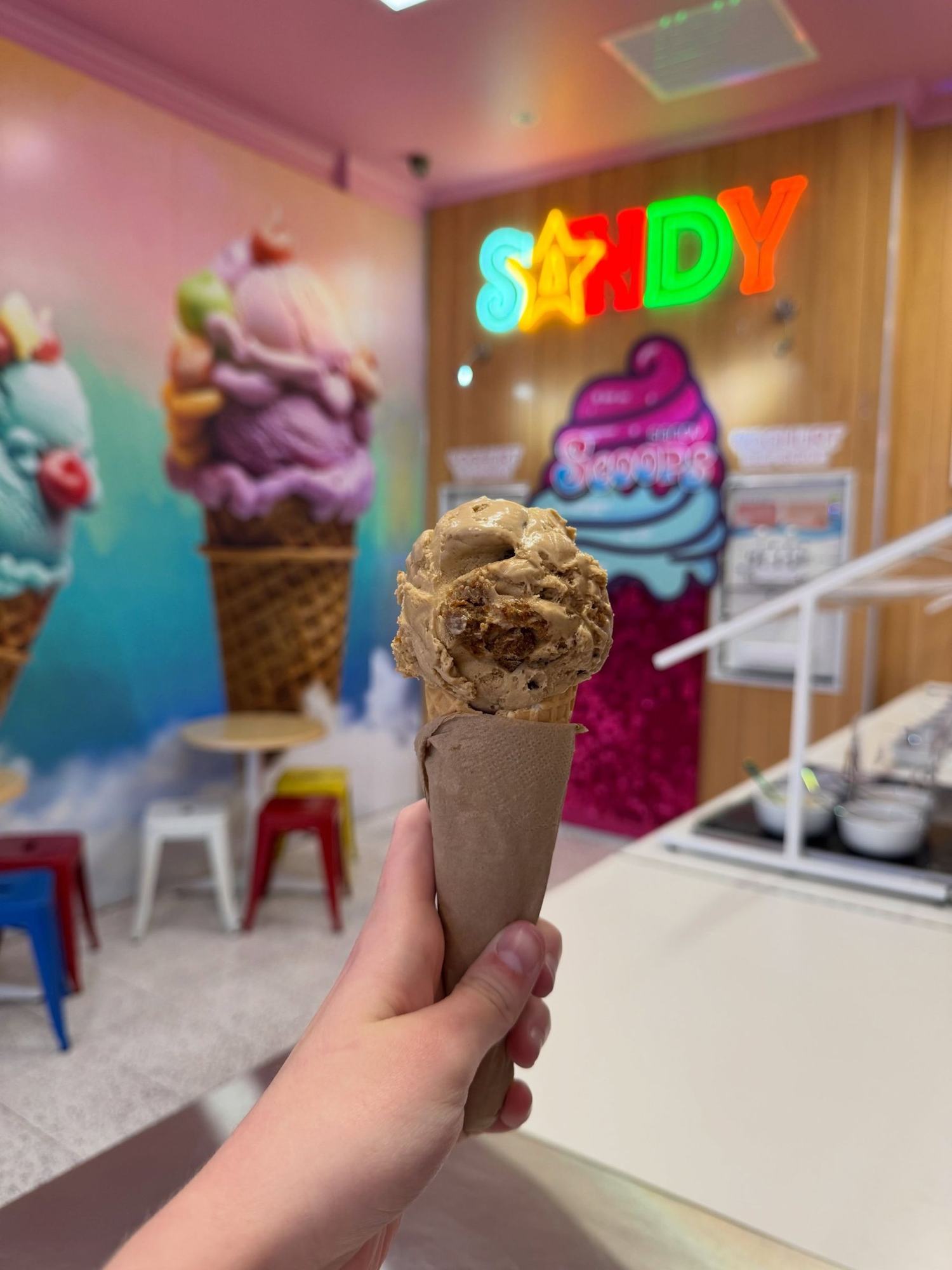 A tiramisu gelato cone held up in the shop