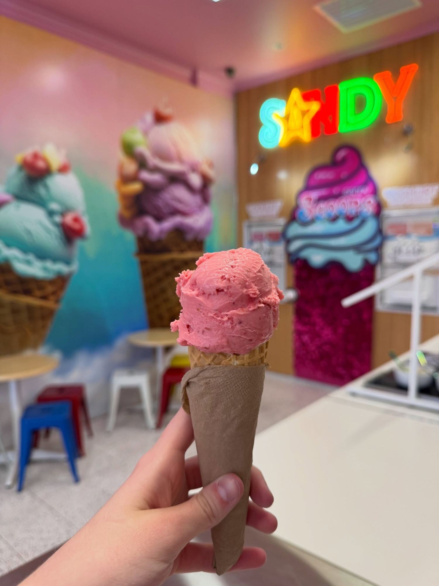 A raspberry sorbet cone in front of the sequin wall